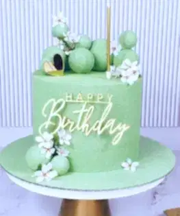 Торт нежно-зеленый с сахарными цветами, шоколадными шарами и топпером